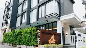 Un edificio moderno con amplios ventanales, un jardín cuidado y una entrada destacada.