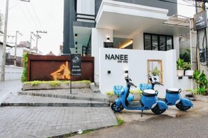 Un bâtiment moderne avec une enseigne indiquant « NANEE, vieille ville », et un scooter garé devant.