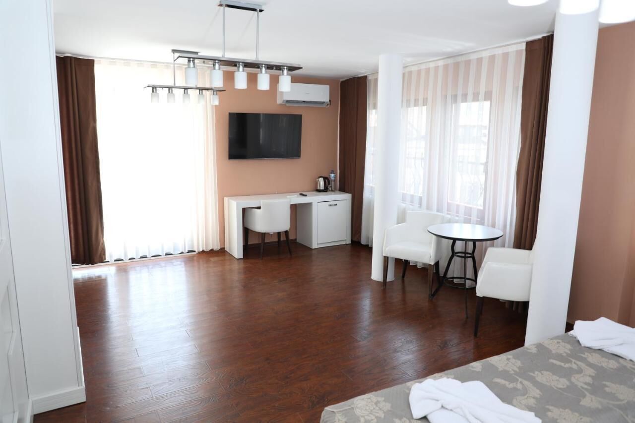 Een hotelkamer met houten vloer, een bureau, een stoel, een bed en een televisie.