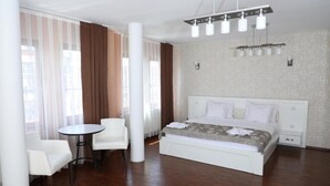 A modern hotel room with a large bed, a round table, and two chairs. - Bruti Hotel (Prizren)