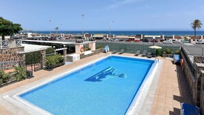 Una piscina con vista al océano y un estacionamiento.