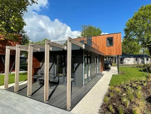 A modern outdoor seating area with a wooden deck and metal pergola structure.