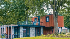 A modern building with a wooden facade, a balcony, and a reflection in a water body. - Family Getaway by Efteling (Kaatsheuvel)
