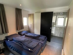 Un dormitorio compacto con cama, mesita de noche, armario y puerta que da al baño.