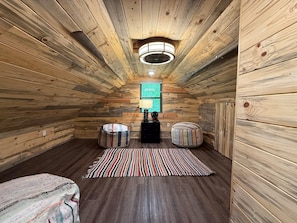 Cozy attic retreat with a sloped ceiling, central light fixture, and plush bed.