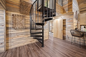 Stunning spiral staircase leads to a spacious dining area with a functional table and chairs.
