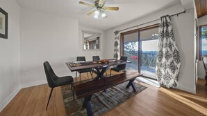 A dining area with a wooden table, black chairs, a ceiling fan, and a view of the outdoors.