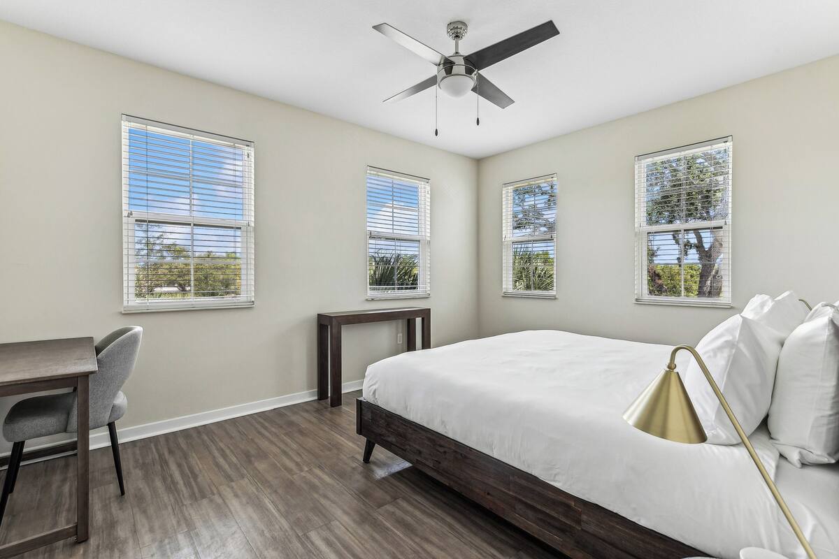 A bedroom with a bed, a desk, and a chair.