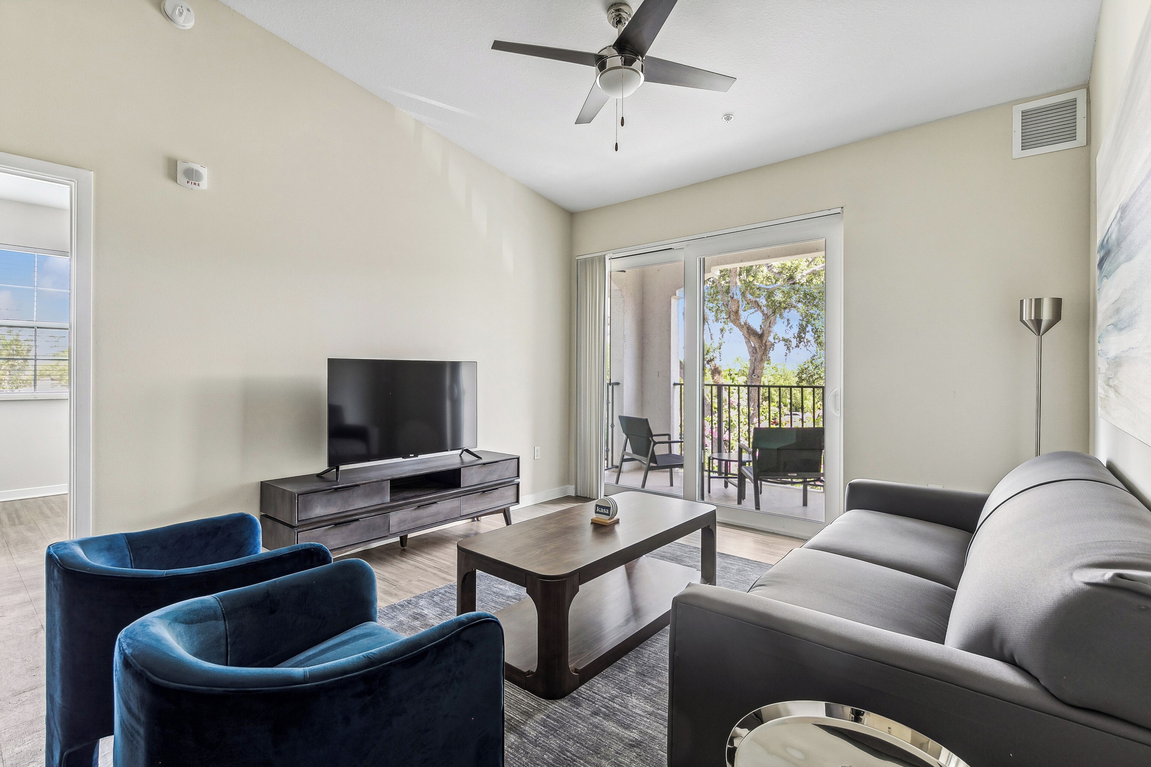 A modern living room with a flat-screen TV, dark sofas, and a coffee table.