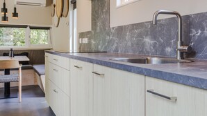 A modern kitchen with a marble countertop, stainless steel sink, and wooden cabinets. - Cozy Lodge Near the Beach (Kamperland)