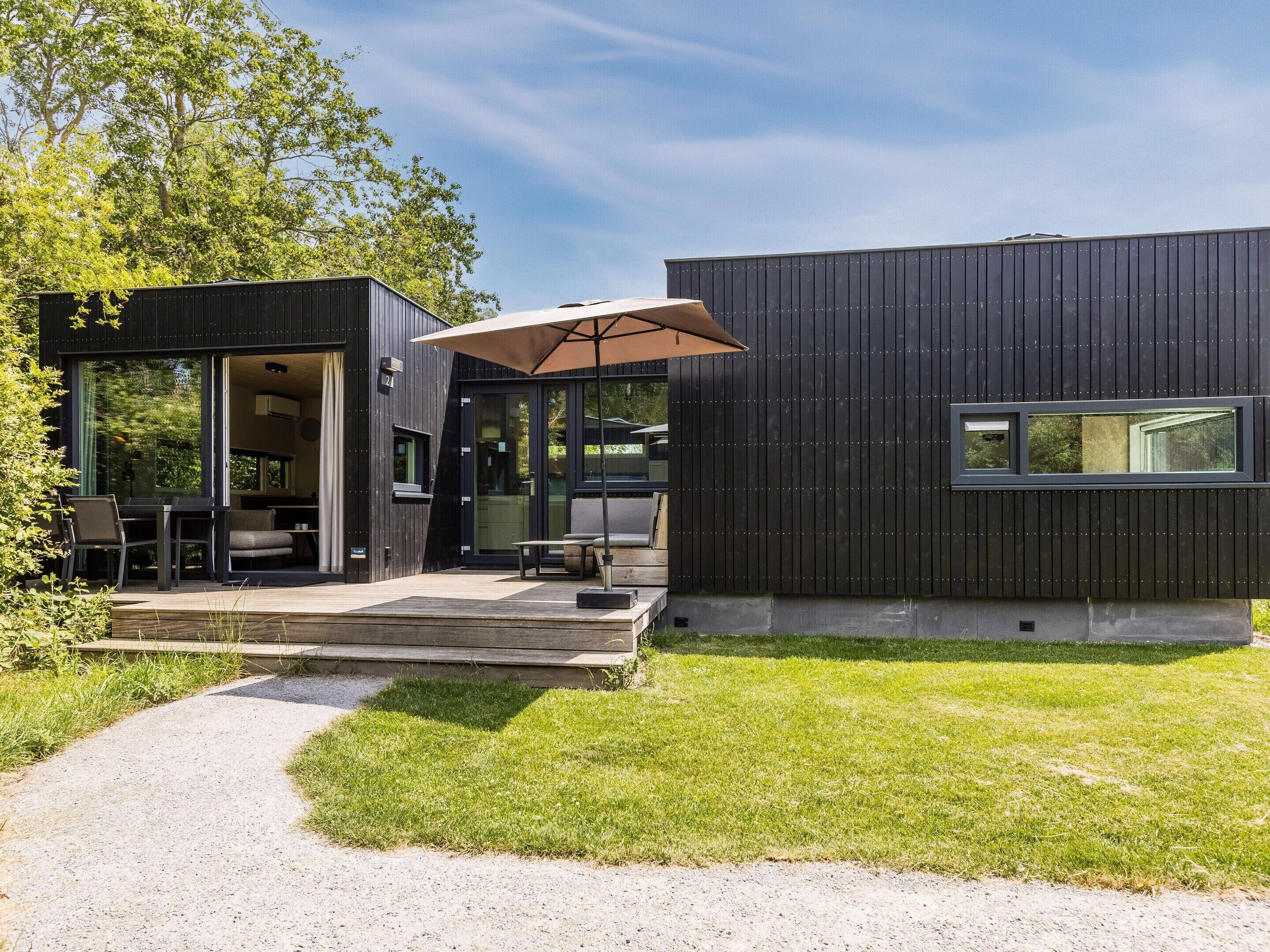 A modern house with a deck, outdoor seating, and a large umbrella.
