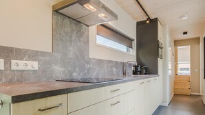 A modern kitchen with a marble backsplash, stainless steel appliances, and a wooden floor. - Cozy Lodge Near the Beach (Kamperland)
