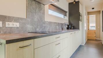 A modern kitchen with a marble backsplash, stainless steel appliances, and a wooden floor.