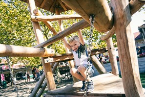 Une structure de jeu en bois sur laquelle un enfant est en train de grimper.