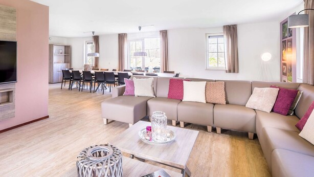 A modern living room with a sofa, coffee table, and dining area. - Villa in Weerterbergen With Private Sauna (Weert)