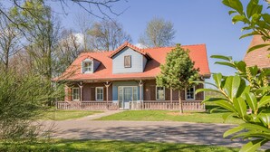 A two-story house with a red roof, a front porch, and a small attached garage. - Villa in Weerterbergen With Private Sauna (Weert)