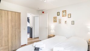 A hotel room with a large bed, a wardrobe, a desk, and a bathroom visible through an open door. - Villa in Weerterbergen With Private Sauna (Weert)