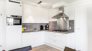 A modern kitchen with white cabinets, a built-in oven, a gas stove, and a stainless steel range hood. - Villa in Weerterbergen With Private Sauna (Weert)