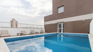 A rooftop swimming pool with lounge chairs and a view of the city skyline. - Akile Bela Vista Tatro Renault (São Paulo)