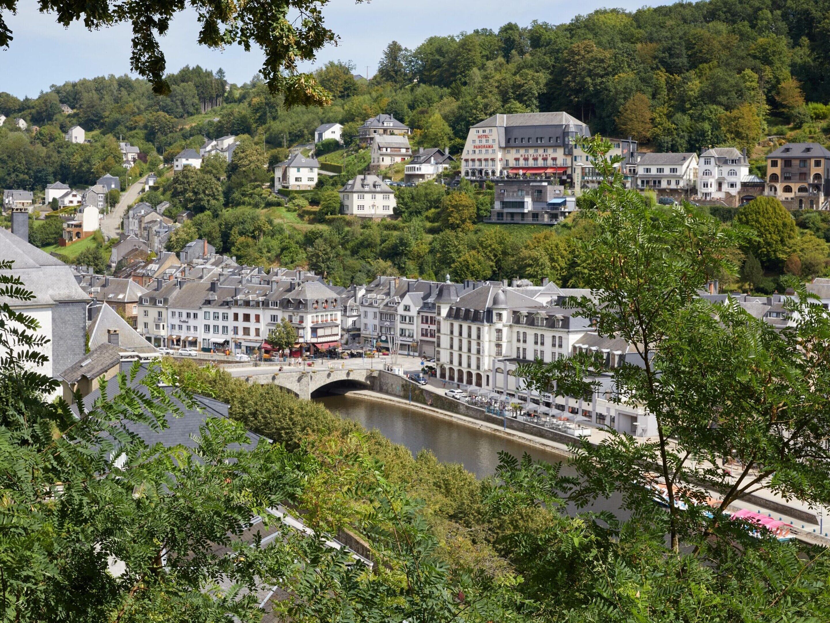 Eine Stadt am Fluss mit einer markanten Brücke, historischen Gebäuden und üppigem Grün.