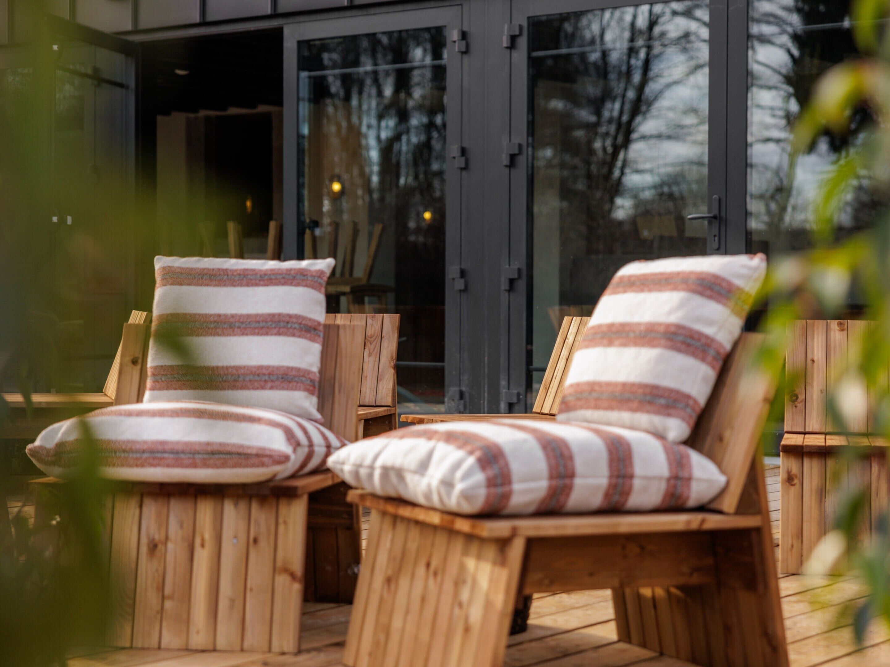 Two wooden lounge chairs with striped cushions on an outdoor deck.