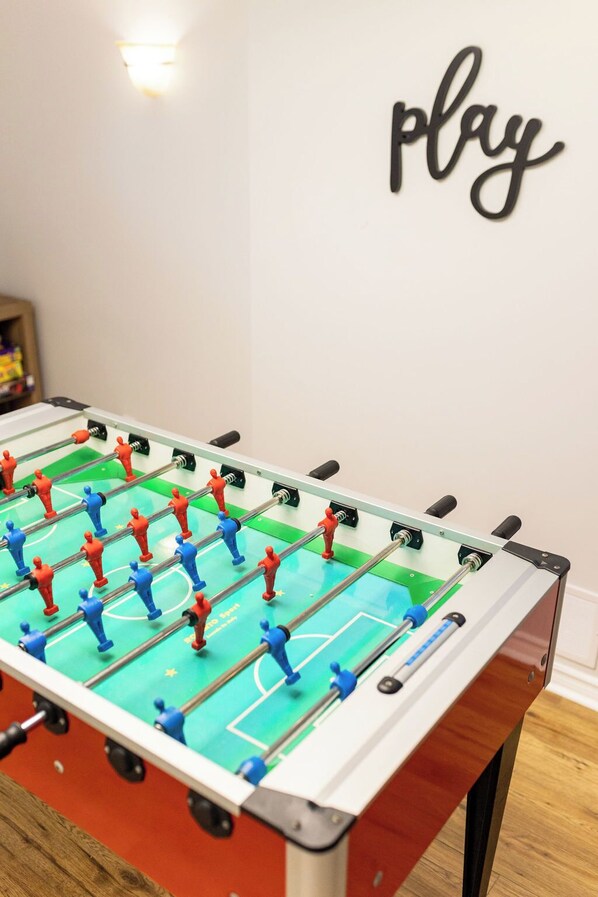 A foosball table with a wall-mounted sign that says "play".