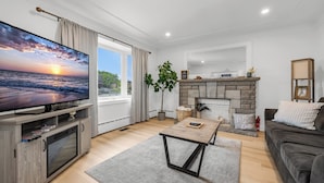 Una sala moderna con televisor, chimenea, sofá y vista al atardecer.