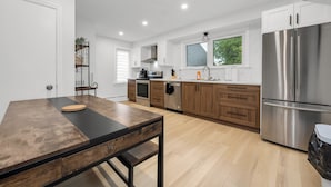 Una cocina moderna con armarios de madera, electrodomésticos de acero inoxidable y un amplio ventanal que aporta luz natural.