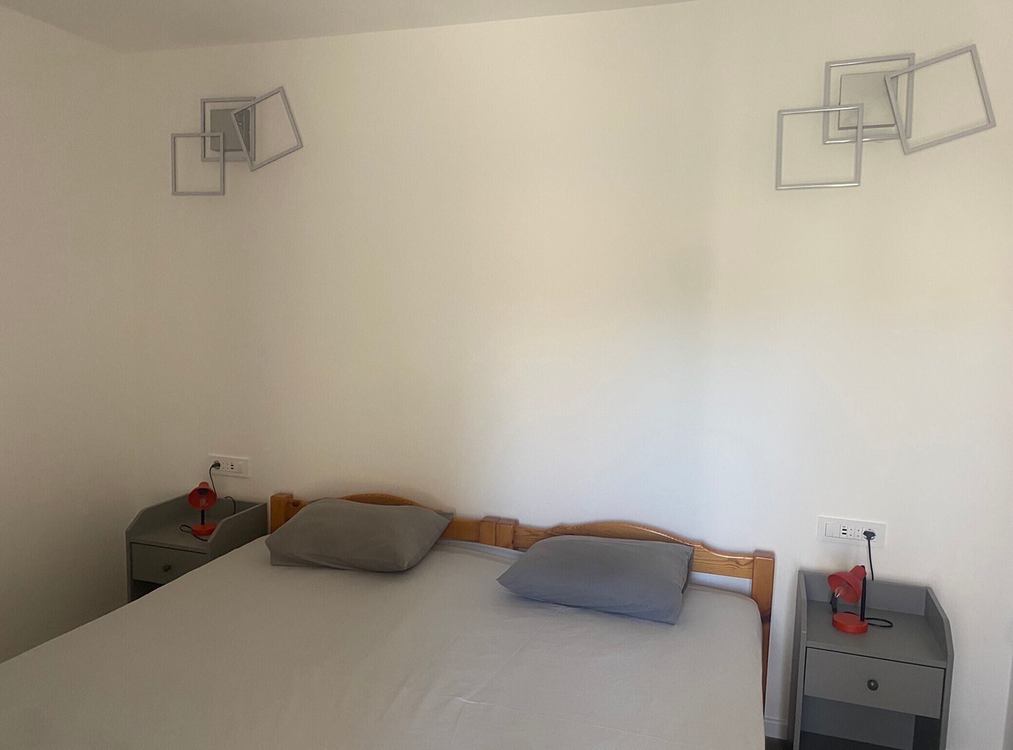 A simple room with a bed, two bedside tables, and a wall with geometric wall art.