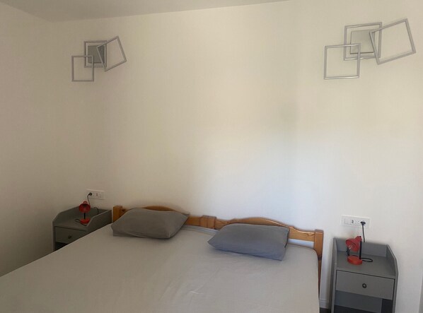 A simple room with a bed, two bedside tables, and a wall with geometric wall art.