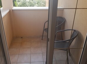 Enjoy a peaceful retreat on this balcony with a window and two comfortable chairs.