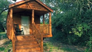 Een houten vakantiehuis met veranda, een deur en een stoel.