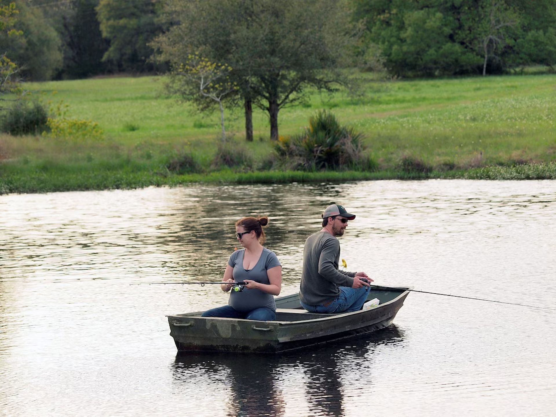 Twee personen in een klein roeibootje op kalm water.