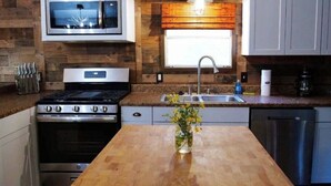 Una cocina con estufa, horno, microondas, lavaplatos y armarios.