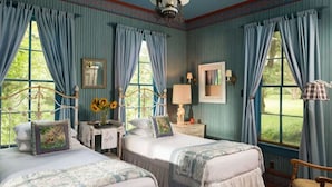 Une chambre avec deux lits, une coiffeuse avec un miroir et une fenêtre avec des rideaux.
