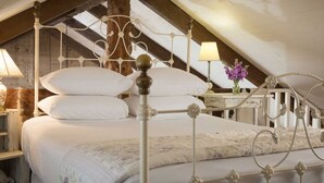 A high-ceilinged attic bedroom with a four-poster bed, wooden beams, and a small table with a lamp and flowers. - Cozy Loft Suite-Part of Dog Trot House-Shared Pool, Fireplace Ranch Fun Options (Cat Spring)