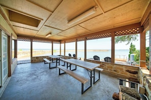 Un área de estar al aire libre con techo y vista a la playa y al mar.