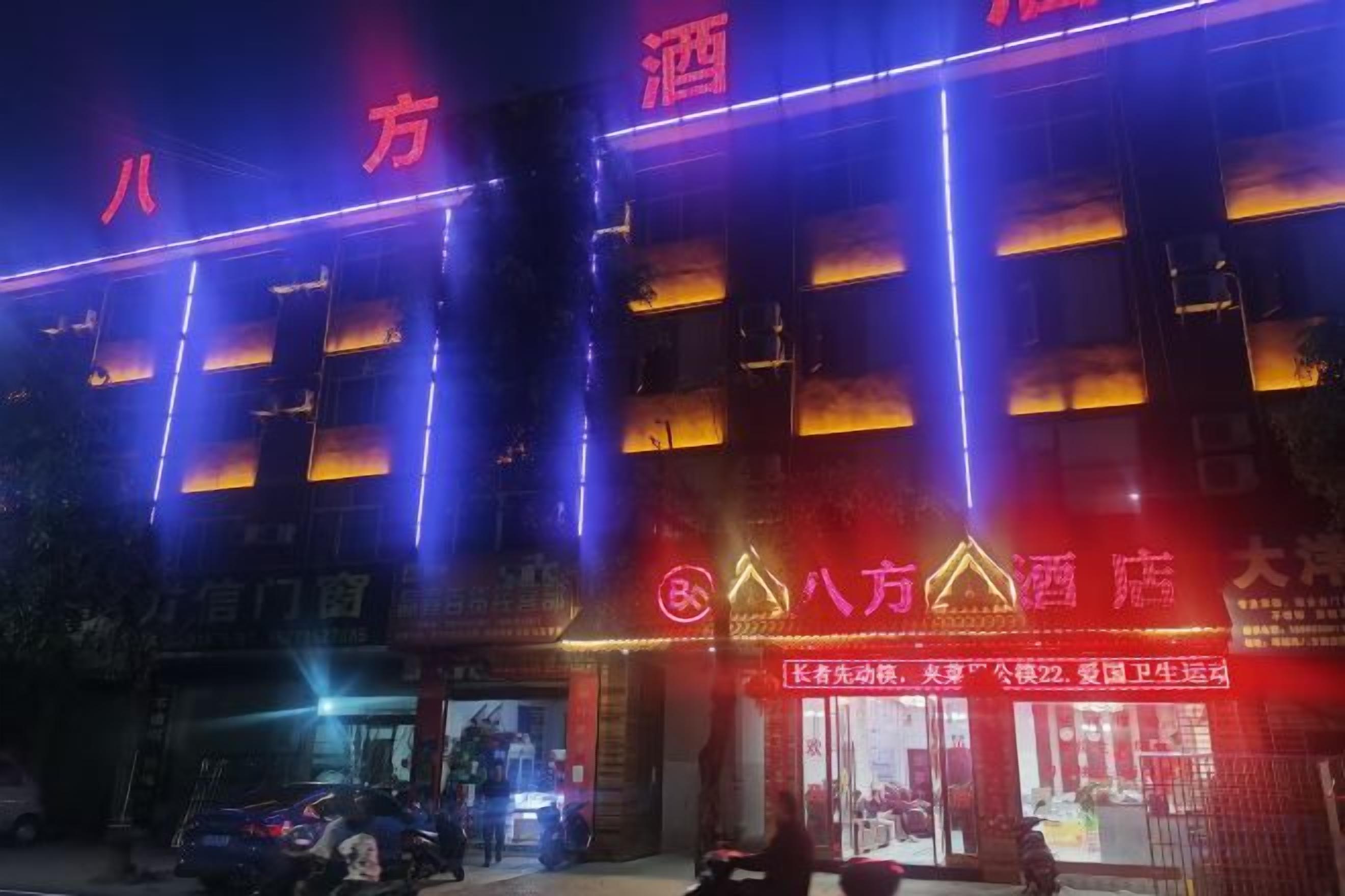 A hotel with multiple floors, illuminated signage, and a visible entrance.