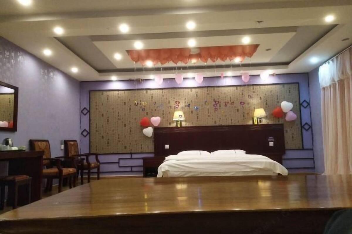 A hotel room with a large bed, a desk, and chairs.