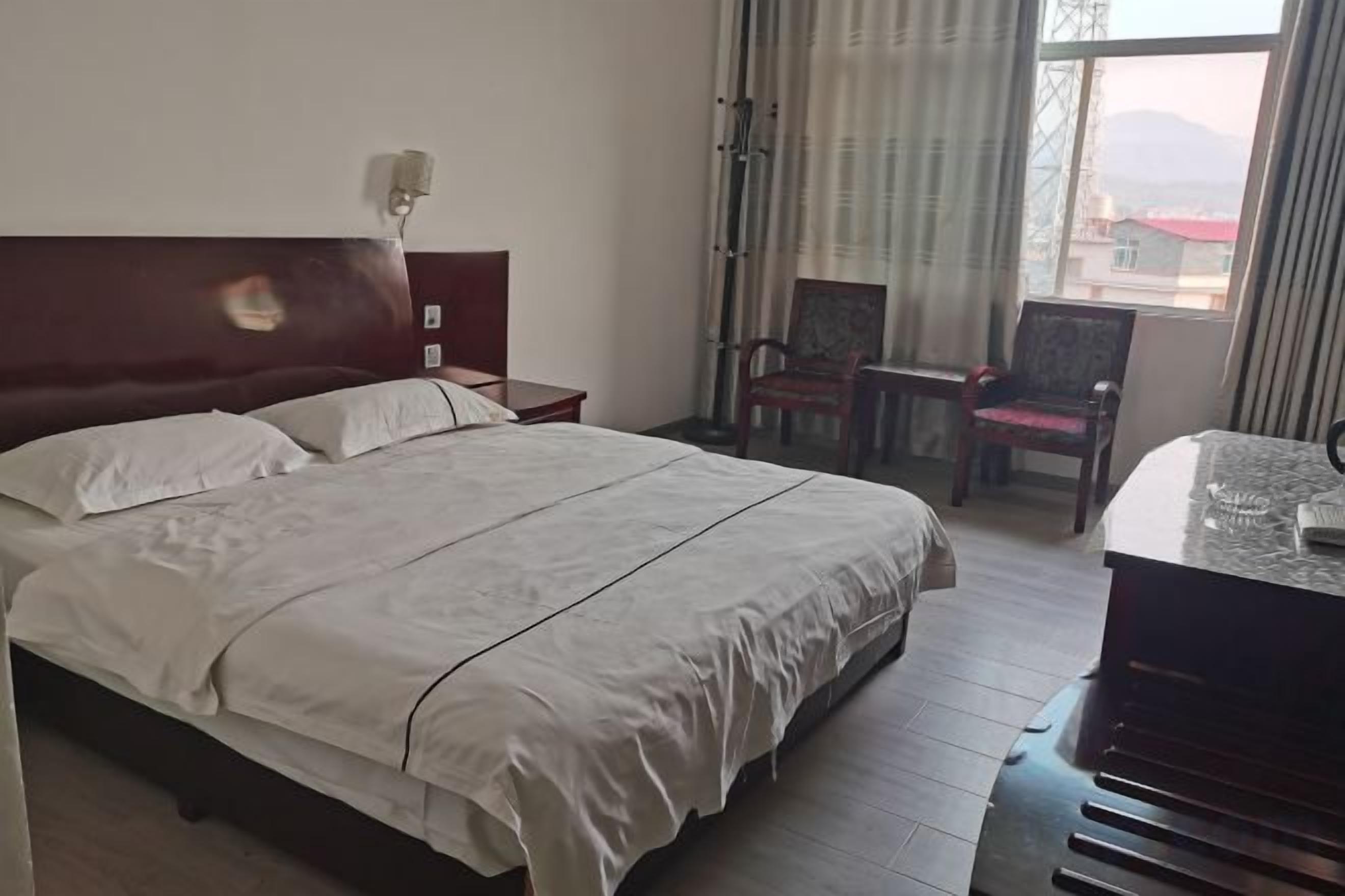 A hotel room with a large bed, a desk, and a chair.