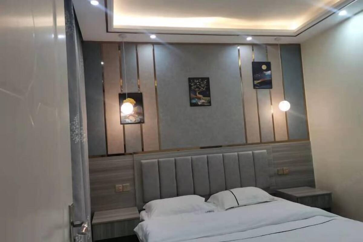 A modern bedroom with a large bed, bedside tables, and wall-mounted lighting.