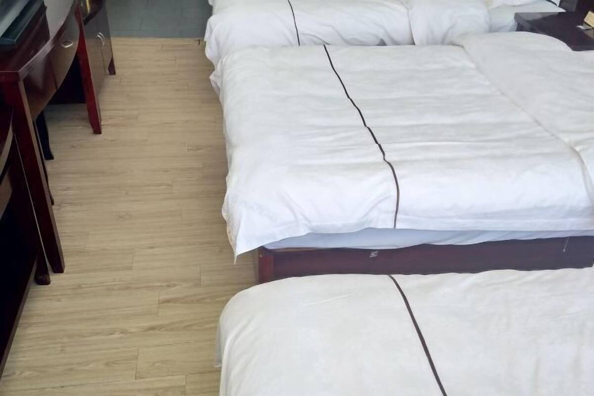 A hotel room with two beds, wooden furniture, and a tiled floor.