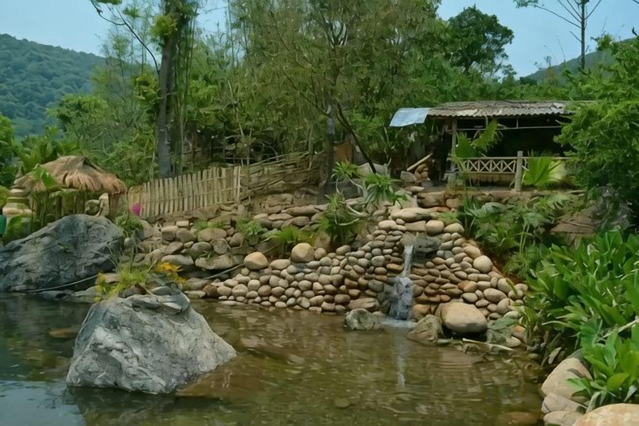 Un paisaje natural con un estanque, rocas y una estructura de madera.