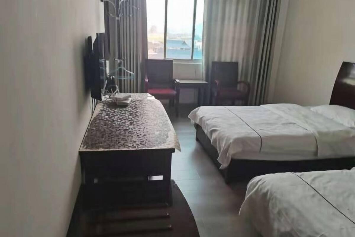 A hotel room with a bed, a desk, a chair, and a TV.