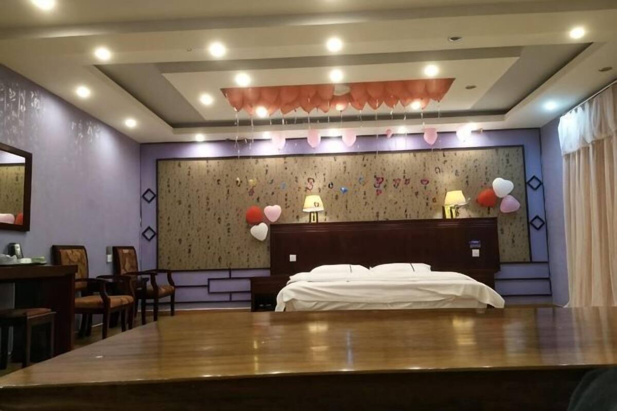 A hotel room with a large bed, a desk with a chair, a dresser, and a large mirror on the wall.