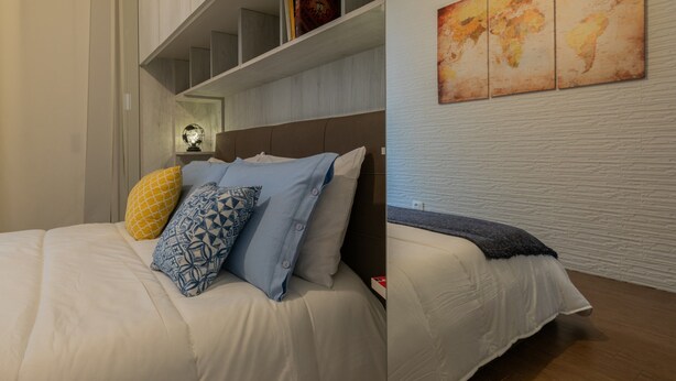 A bedroom with a bed, pillows, a shelf with books, and a world map on the wall. - Turin World Apartment by Wonderful Italy (Turin)