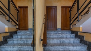 A set of marble stairs with wooden doors and black railings. - Turin World Apartment by Wonderful Italy (Turin)