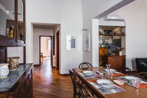 A dining area with a wooden table set for four, flanked by chairs, and a kitchen area with cabinets and appliances.