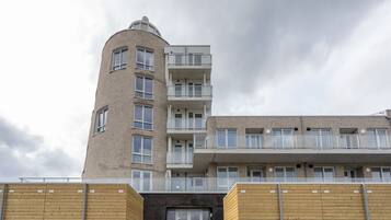 A multi-story building with a curved corner, balconies, and a flat roof.
