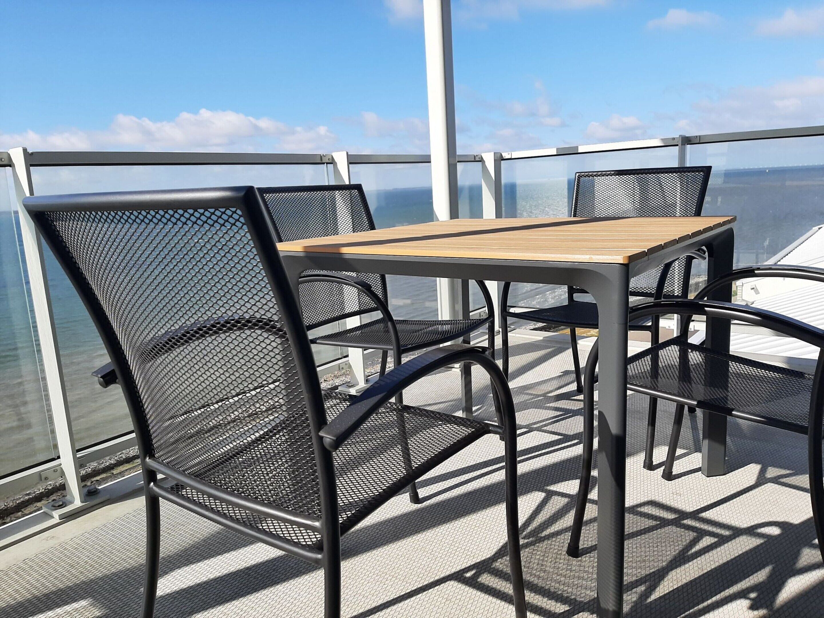 Ein Tisch und Stühle auf einem Balkon mit Meerblick.